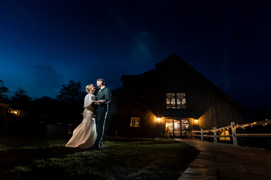 bride and groom on wedding night in front of barn